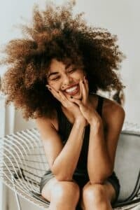 woman smiling with hands on her face